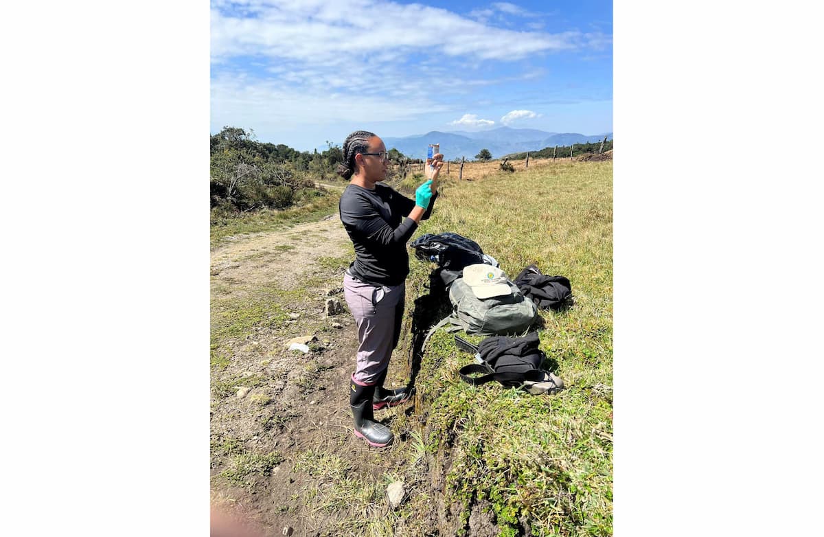 Dr. Davis-Powell fills a syringe while standing in a field, surrounded by medical backpacks