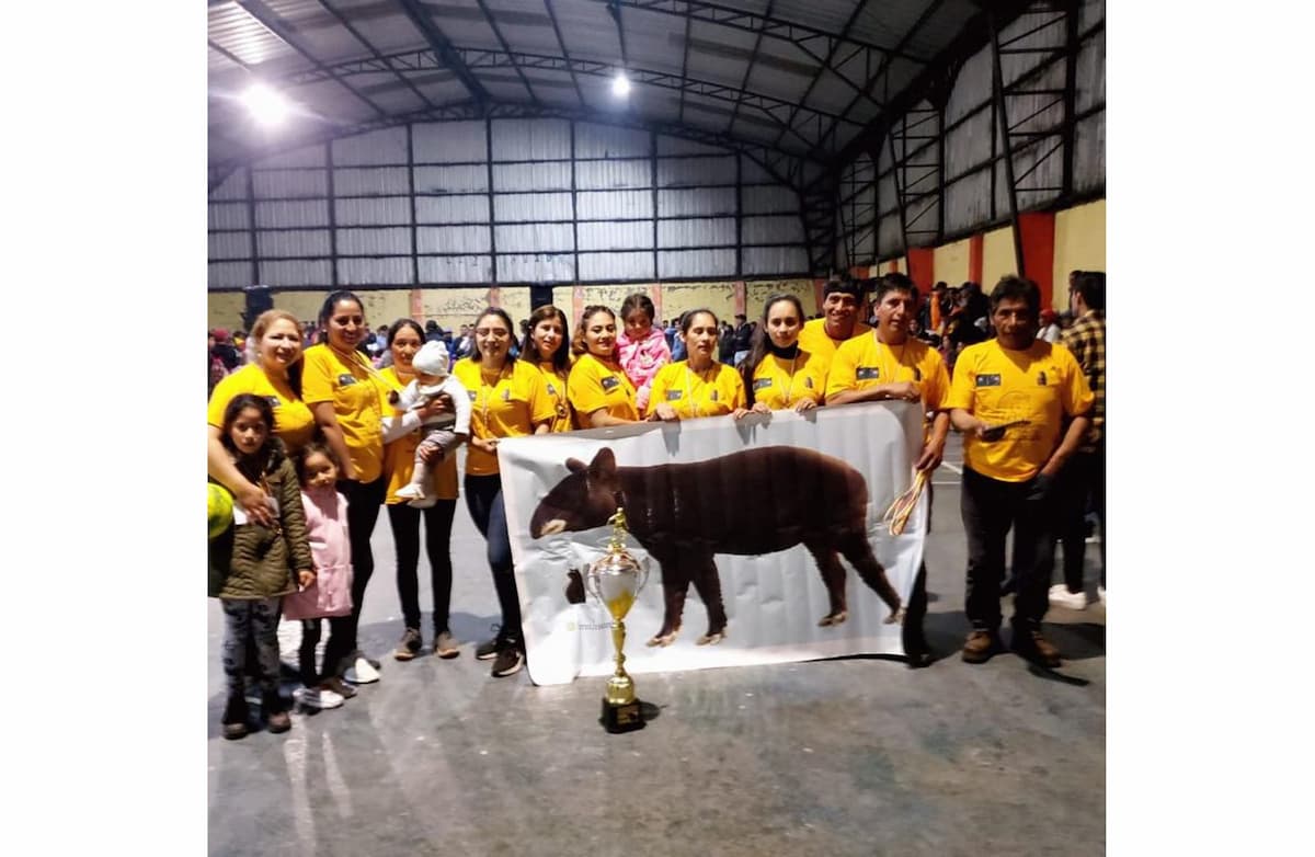 A group of Ecuadorian soccer enthusiasts pose next a trophy and a large banner of a tapir