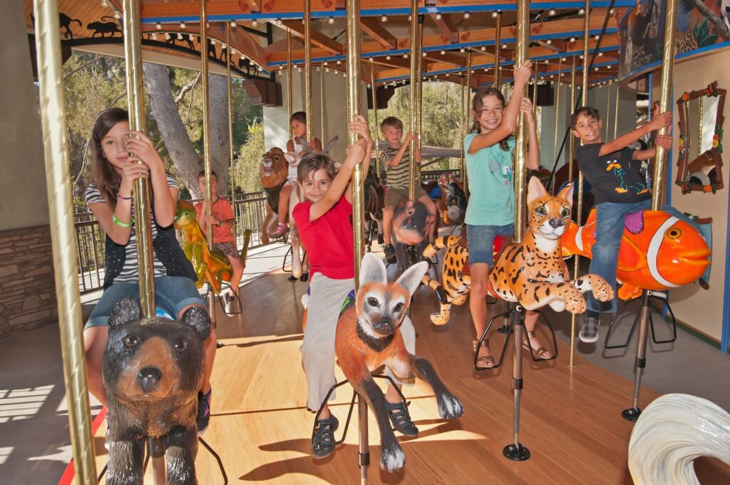 Children riding on different carousel animals.