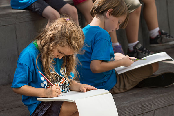 Young people take a moment to reflect in a Nature Journaling activity.