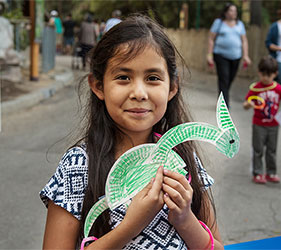 Girl holds homemade craft art at Dia de los Niños/Children's Day