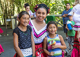 Girls pose with a dancer at Dia de los Niños/Children's Day