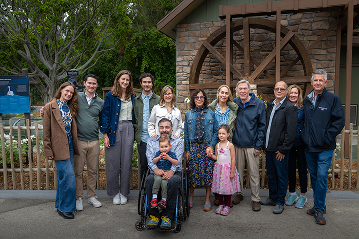 A multi-generational family stands in front of a water wheel at the zoo