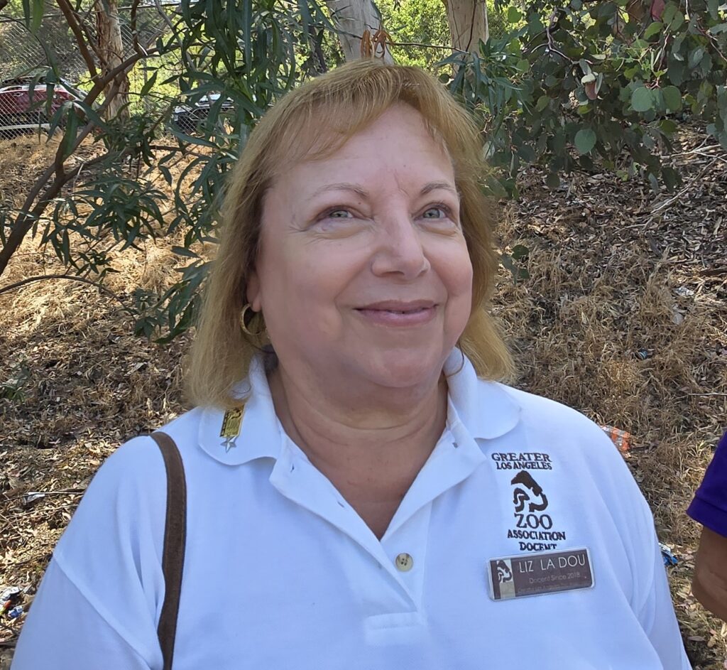 A photo of Liz LaDou wearing a GLAZA uniform with a wooded background.